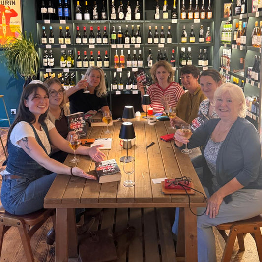Group of people sitting around a wooden table in a hastings wine bar
